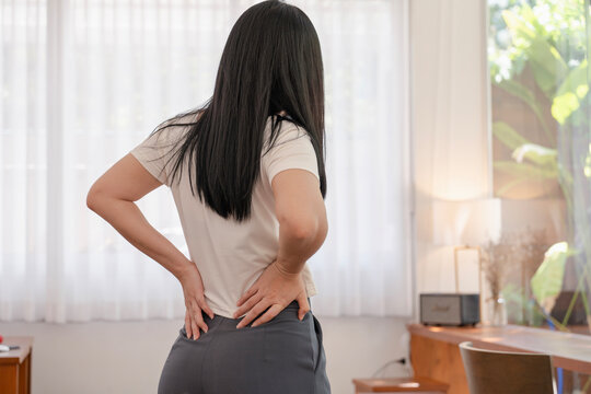 asian woman having low back pain and spinal compression. adult female with muscle pain after waking up.