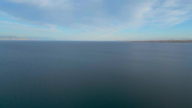 Drone shot Sevan lake, Armenia. Idyllic scene with mountains and cloudy sky landscape. Natural scenery. bird fly over water. Touristic place. Discovery Caucasus. Holiday near lake, water, sea. 