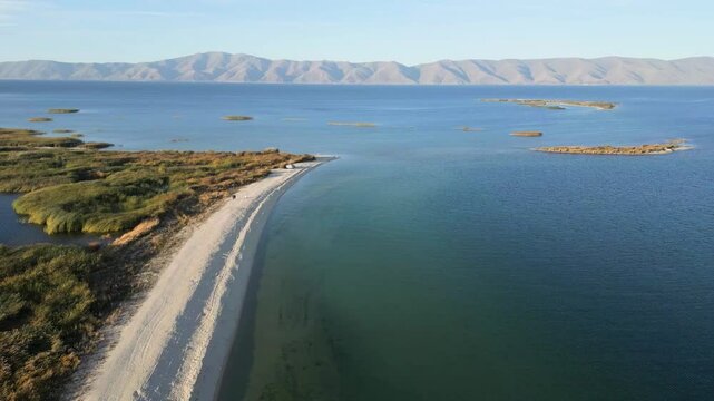  Scenic view of a tranquil shoreline and lush vegetation along a serene blue lake. Aerial shot Lake Sevan in Armenia, Caucasus. Diablo lake aerial view. Wild white beach near  mountain lake. 