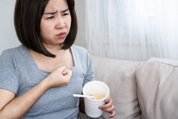 Asian woman suffering from bloating, indigestion after eating noodles, junk food
