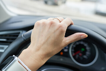 Close up of woman hands on steering wheel of a car. Focus on hand