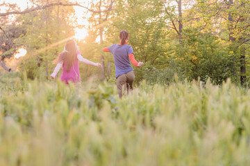 Fototapeta premium Two friends running in a field at sunset, enjoying nature and freedom
