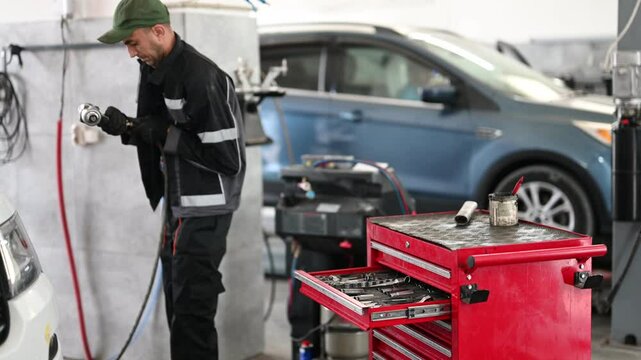 Mechanic preparing for car service and repair in a garage. A toolbox with tools in the foreground and a car in the background.