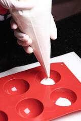 Pouring cream into a silicone mould using piping bag