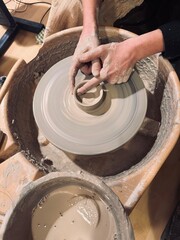 Hands shaping pottery on a spinning wheel in a creative studio
