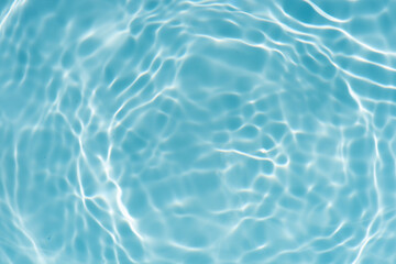 Blue water with ripples on the surface. Defocus blurred transparent blue colored clear calm water surface texture with splashes and bubbles. Water waves with shining pattern texture background.