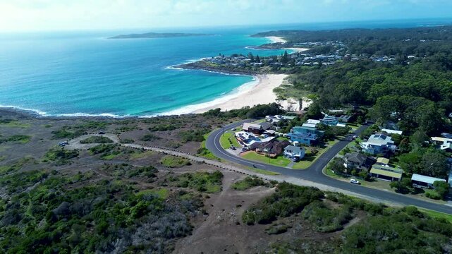 Drone aerial landscape of Cormorant Beach residential housing roads street with sandy bay bushland forest rocky reef Bawley Point Shoalhaven Australia travel tourism