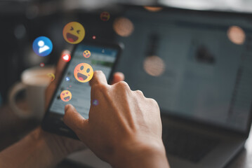Close-up of a hand interacting with a smartphone, showing colorful floating emoji reactions...
