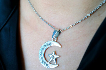 Muslim woman wearing Islamic pendant. Crescent and star symbols of Islam.