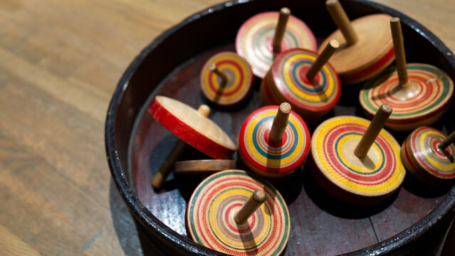 A vibrant collection of wooden spinning tops arranged in a bowl, showcasing colorful patterns and playful design