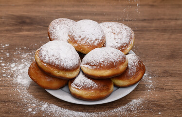 Talerz prawdziwych domowych loczków posypanych sproszkowanym cukrem, smaczne kaloryczne bułeczki drożdżowe 