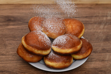 Piękne apetyczne smażone pączki posypywane cukrem pudrem, słodkie przekąski, tłusty czwartek 