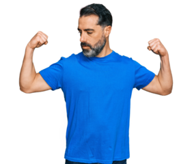 Middle aged man with beard wearing casual blue t shirt showing arms muscles smiling proud. fitness concept.
