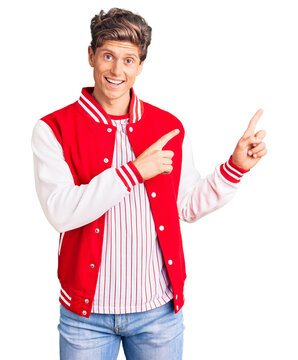 Young handsome man wearing baseball uniform smiling and looking at the camera pointing with two hands and fingers to the side.