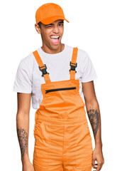 Young handsome african american man wearing handyman uniform winking looking at the camera with...