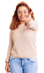 Fototapeta premium Young latin woman wearing casual clothes and diadem smiling friendly offering handshake as greeting and welcoming. successful business.