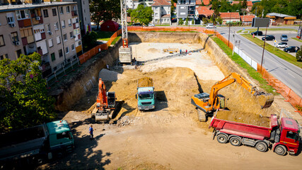 Ariel view excavator is loading a truck with ground on building site