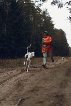 Woman running through the forest with a dogs
