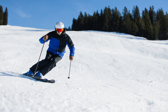 Skier carving on a snowy slope in Kitzb&uuml;hel under a bright blue sky
