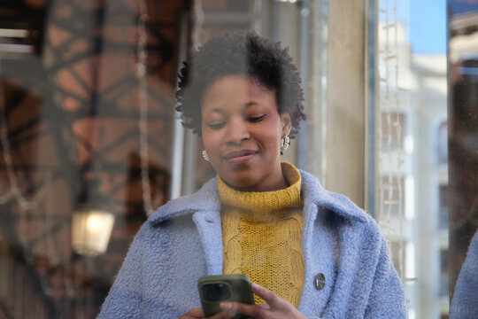 Woman using smartphone standing next to a shop window in the city