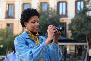 Young tourist taking photos in a city center with a vintage camera