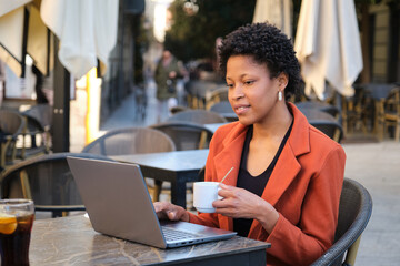 Professional woman working at outdoor cafe with laptop
