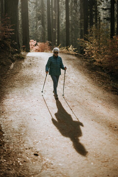 Elderly woman walks along woods road in late afternoon light