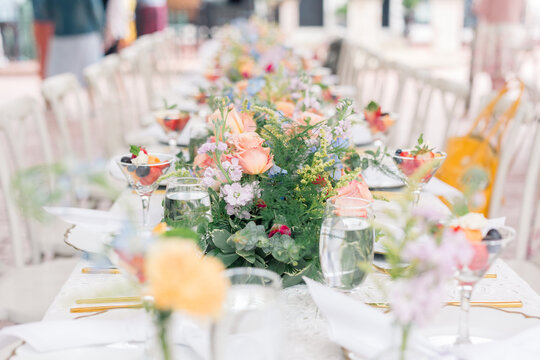 Floral table centerpiece with roses at an elegant outdoor brunch.