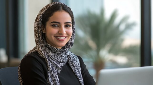 Focused young middle eastern businesswoman smiling while working on laptop computer