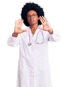 Young african american woman wearing doctor coat and stethoscope doing frame using hands palms and fingers, camera perspective