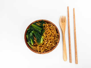 A serving of spicy fried noodles with vegetables and tofu, beautifully presented in a wooden bowl...