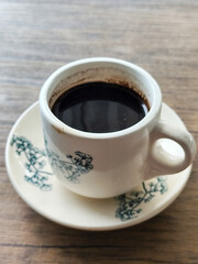 Coffee in a white cup on a wooden table.	