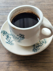 Coffee in a white cup on a wooden table.	