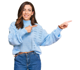 Young brunette woman wearing casual winter sweater smiling and looking at the camera pointing with two hands and fingers to the side.