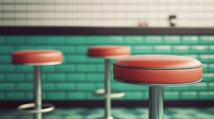 A close-up view of retro-style bar stools with vibrant red cushions against a turquoise-tiled...