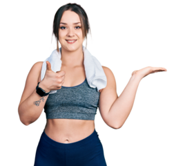Young hispanic girl wearing sportswear and towel showing palm hand and doing ok gesture with thumbs up, smiling happy and cheerful