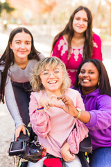 Woman with cerebral palsy making heart shape with hands with friends. international women's day