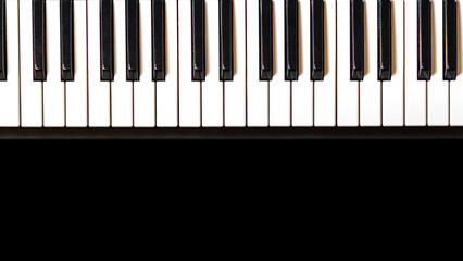 Fototapeta premium Close up true traditional piano keyboard, white and black keys on black background. Music party banner, celebrate poster, concert invitation. Flatlay photography, top view, copy space.