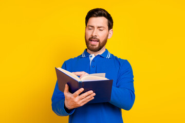 Photo portrait of attractive young man read book dressed stylish blue clothes isolated on yellow color background