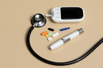 A digital blood glucose monitor placed alongside medical pills and a stethoscope on a clean white...