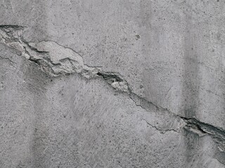 Rough and dirty concrete wall with diagonal crack