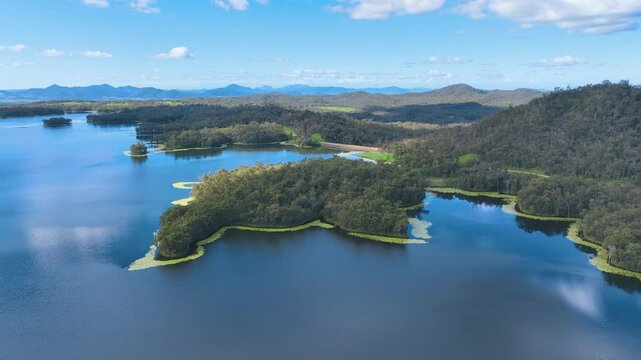 Aerial flies across the vast lake and an island surrounded by swathes of lily pads and covered in dense lush forest Teemburra Pinnacle Mackay Queensland Australia