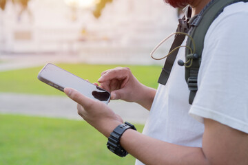 Shot of a handsome young man with backpack standing alone and using his cellphone.