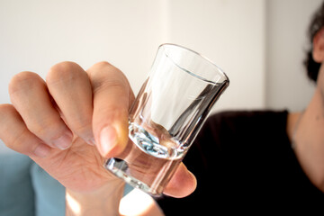 Man holding empty shot glass. Shot glass in model's hand. Tequila equipment. Alcohol consumption idea concept. 