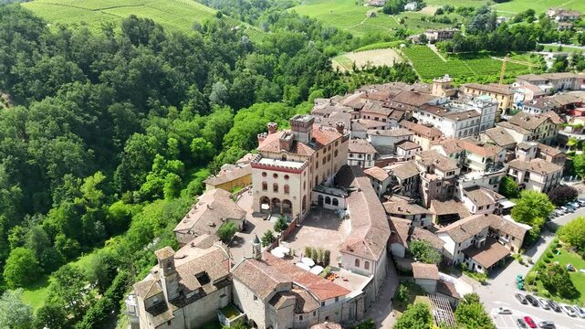 Barolo Castle in Langhe Wine Region, Cuneo, Piedmont, Italy. 4K Aerial view of the village and the vineyards, flying backward ascending, revealing the town.