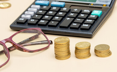 Financial planning concept with a calculator, coins, and a eyeglasses on the table.