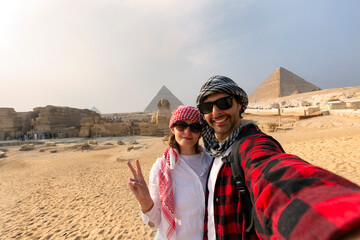 Young Couple taking selfie photo in front of the Great Pyramids of Giza, Egypt