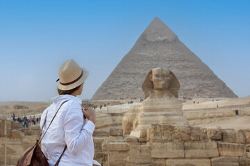 Back view of a woman wearing a hat, looking at the  great pyramids in Egypt