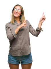 Young beautiful woman over isolated background smiling and looking at the camera pointing with two hands and fingers to the side.