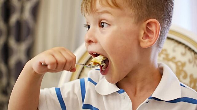 Cute little boy eating cake with spoon. 
